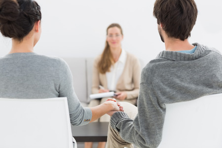 Blurred female financial adviser in meeting with young couple at homeの写真素材