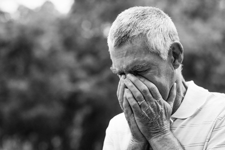 Worried senior man with head in hands at the parkの写真素材