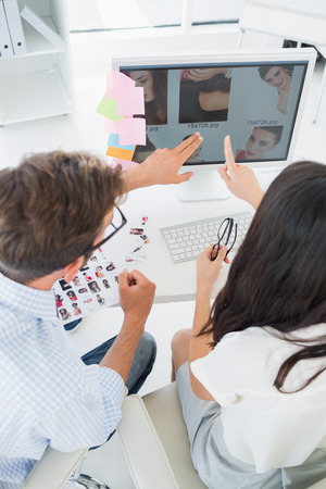 Rear view of casual photo editors working on computer in a bright officeの写真素材