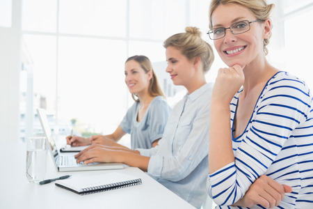 Portrait of three young people working in a bright officeの写真素材