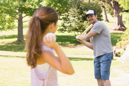 Father and daughter playing baseball in the park
