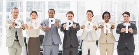 Diverse business team holding up letters spelling support in the officeの写真素材