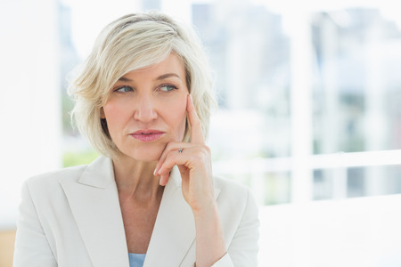 Close-up of a mature businesswoman looking away in a bright officeの写真素材