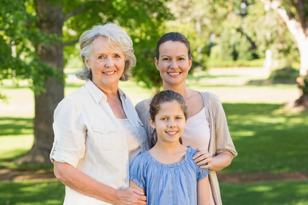 Portrait of a smiling woman with grandmother and granddaughter at the parkの写真素材