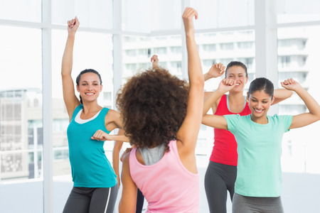 Cheerful fitness class and instructor doing pilates exercise in bright roomの写真素材