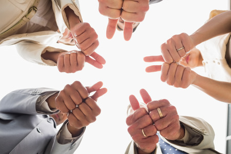 Business team looking down at the camera showing thumbs up in the office