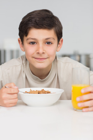 Portrait of a smiling young boy enjoying breakfast in the kitchen at home