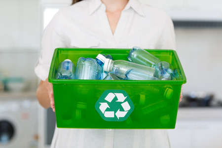 Closeup mid section of a woman carrying box with recycling symbol in the houseの写真素材