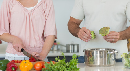 Midsection of couple preparing food together at kitchen counterの写真素材