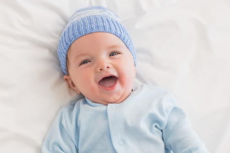High angle portrait of cheerful baby boy in bed