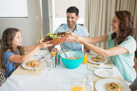 Side view of happy family of three sitting at dining table in the homeの写真素材