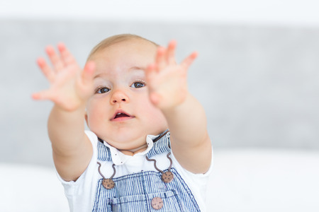 Closeup portrait of a cute baby holding out his hands over blurred backgroundの写真素材