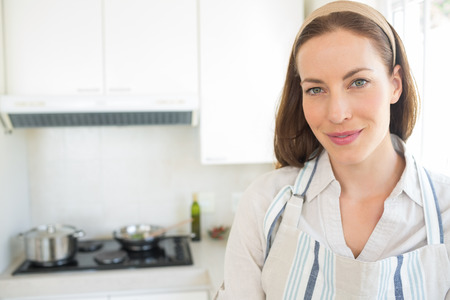 Closeup portrait of a smiling young woman in the kitchen at homeの写真素材