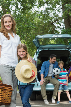 Portrait of mother and daughter with father and son sitting in car trunkの写真素材