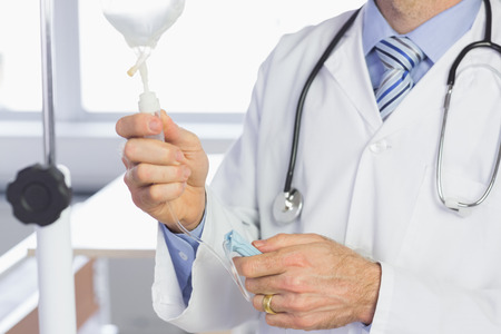 Mid section of male doctor examining IV drip in hospitalの写真素材