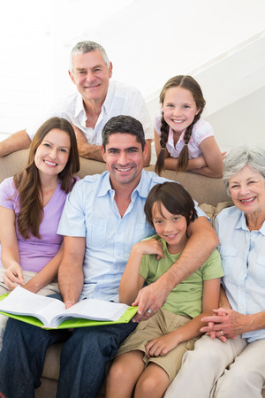Portrait of happy multigeneration family with book at homeの写真素材