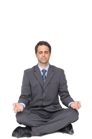 Peaceful businessman meditating in lotus pose on white backgroundの写真素材