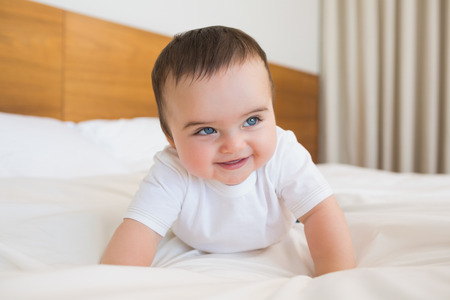 Happy baby boy looking away in bedの写真素材