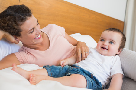 Happy baby boy and mother in bed