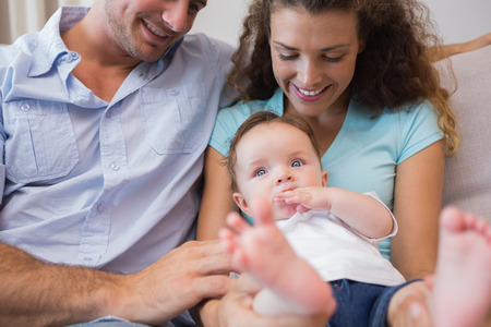 Happy parents looking at cute baby in living room