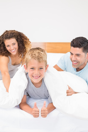 Cute young family messing about on bed at home in bedroomの写真素材