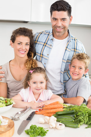 Smiling family preparing vegetables together at home in kitchenの写真素材