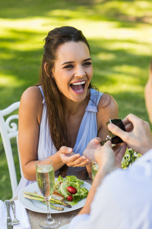 Man proposing a cheerful woman while they have a romantic date at an outdoor caf&#xc3;&#xa9;の写真素材