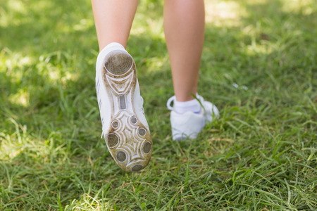 Close-up low section of a young woman in sports shoes jogging at the parkの写真素材