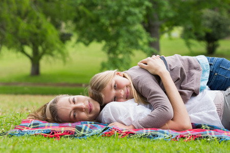Side view portrait of a relaxed mother and daughter lying at the parkの写真素材