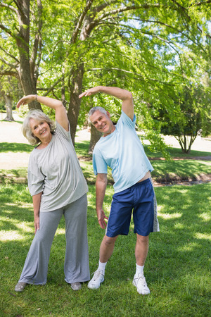 Full length portrait of a mature couple stretching hands at the parkの写真素材