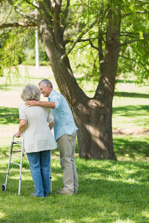 Rear view of a mature man assisting woman with walker at the parkの写真素材