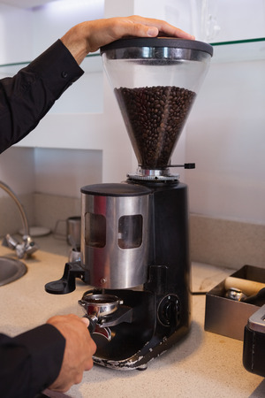 Barista grinding coffee beans in a cafeの写真素材