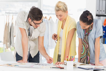 Three fashion designers discussing designs in a studioの写真素材