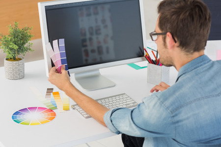 Rear view of a casual male photo editor using computer in officeの写真素材