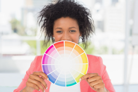 Portrait of a beautiful young woman holding color wheel at bright officeの写真素材
