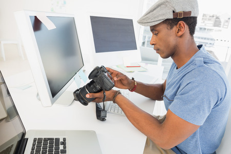Side view of a male photo editor looking at digital camera in his officeの写真素材