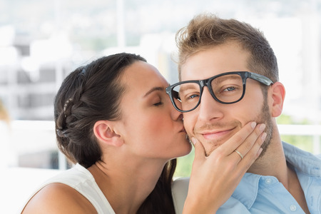 Attractive young designer getting a kiss from a co worker in creative officeの写真素材