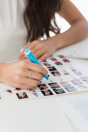 Editor working at desk marking a contact sheet in creative officeの写真素材