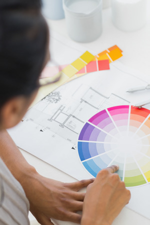 Interior designer looking at colour wheel at her desk in creative officeの写真素材