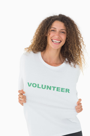 Happy volunteer showing her tshirt to camera on white backgroundの写真素材