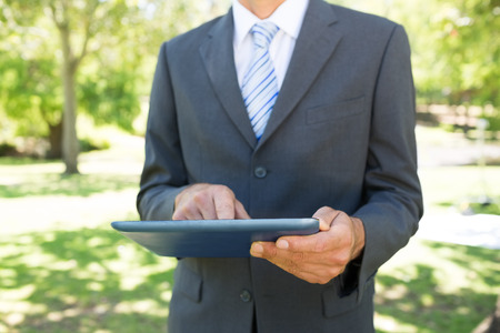 Midsection of businessman using digital tablet in parkの写真素材