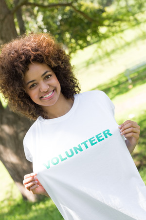 Portrait of smiling environmentalist holding volunteer tshirt in parkの写真素材