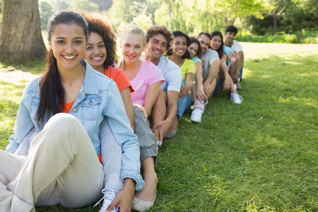 Portrait of confident friends sitting in a line on campus