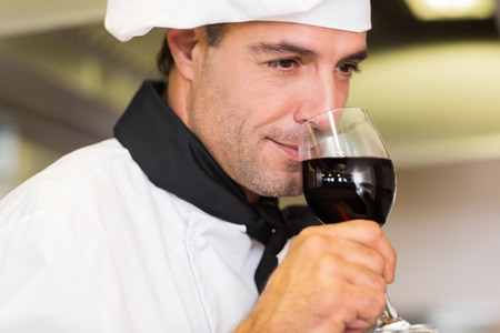 Closeup of a male chef smelling red wine in the kitchenの写真素材