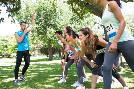 Trainer whistling while marathon runners ready to race in the park