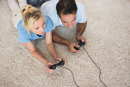 High angle view of a couple playing video games on area rug at homeの写真素材