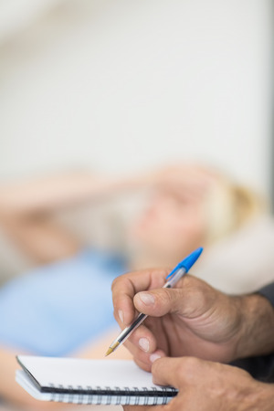 Closeup of hands writing diary with blurred woman in the backgroundの写真素材