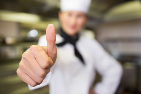Portrait of a blurred female cook gesturing thumbs up in the kitchenの写真素材