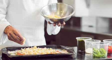 Closeup mid section of a male chef garnishing food in the kitchenの写真素材