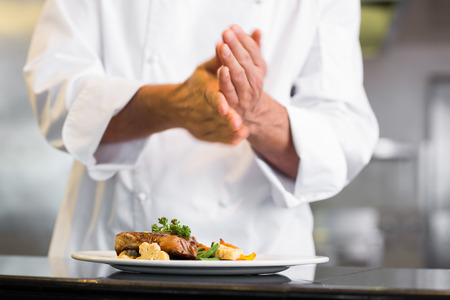 Closeup mid section of a chef putting salt in the kitchenの写真素材